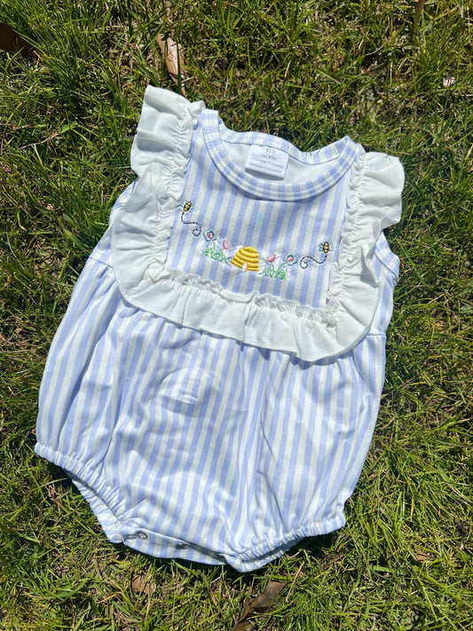 Child's bubble romper with blue stripe pattern and ruffled chest. Embroidered design with beehive, flowers, and bees.